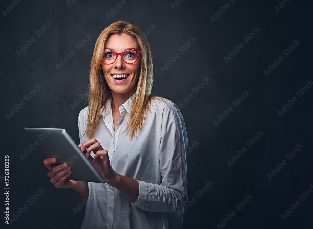 A blond female holds tablet PC on grey background. A blond female holds tablet PC on grey background.