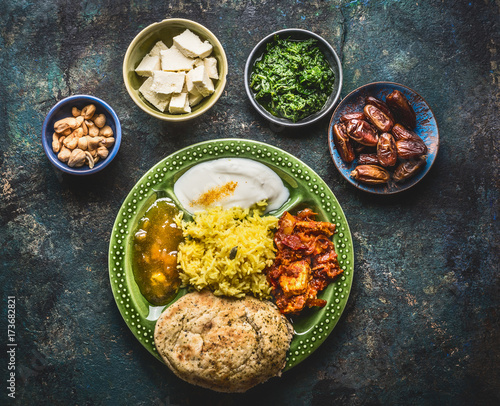 Various indian food bowls with curry, yogurt ,rice,bread ,chutney, paneer cheese and spices on dark rustic background, top view