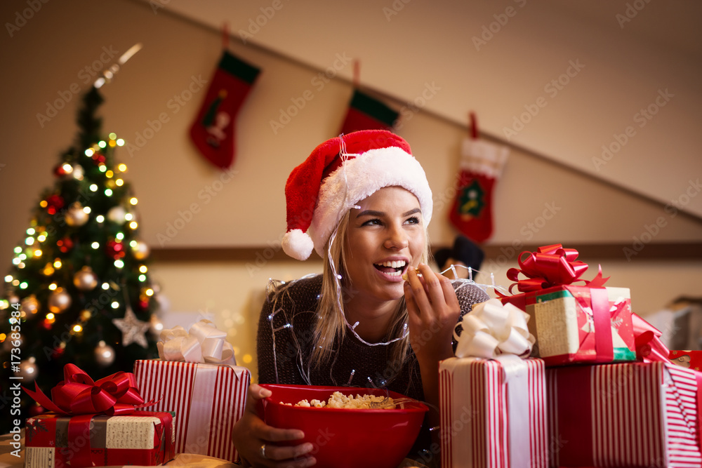Gorgeous young girl with presents and popcorn for Christmas holidays lying on the bad. Gorgeous young girl with presents and popcorn for Christmas holidays lying on the bad.