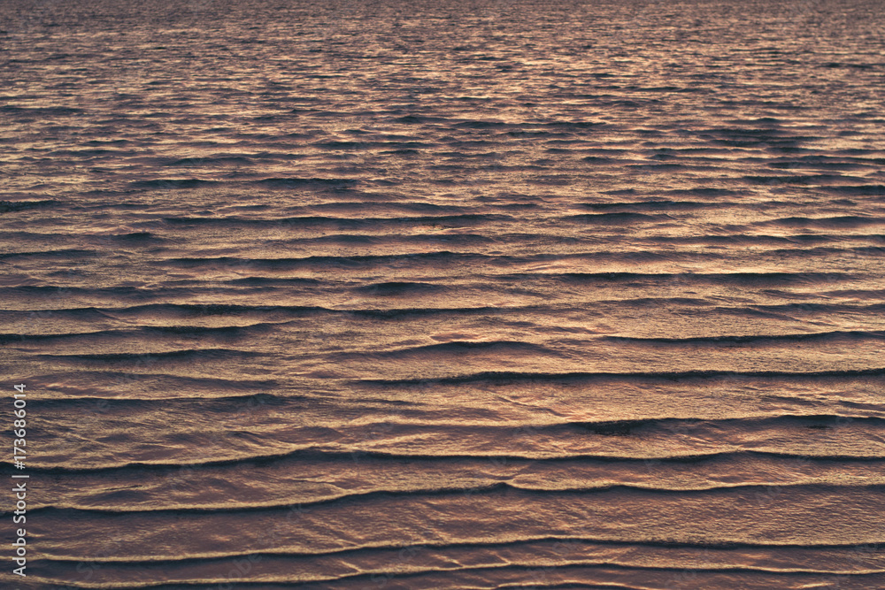 Texture of shallow waves colored by purple light of the setting sun Texture of shallow waves colored by purple light of the setting sun