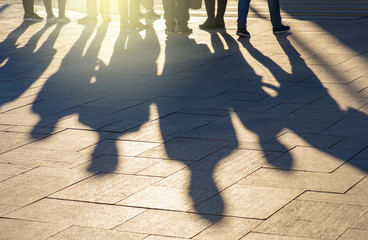 Shadows and silhouettes of people at a city during sunset