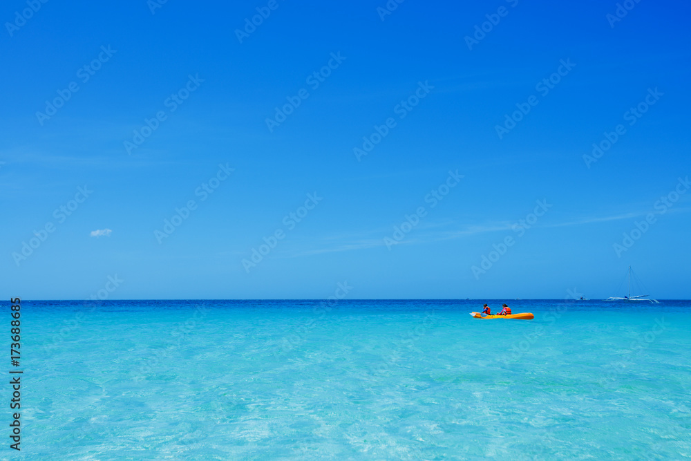 Two chirdren kayaking at tropical sea on yellow kayak