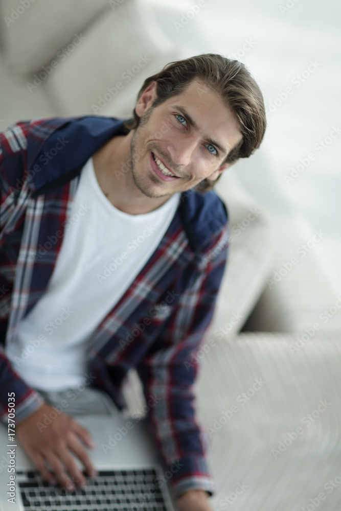 young man working on laptop and looking at camera. view from above young man working on laptop and looking at camera. view from above