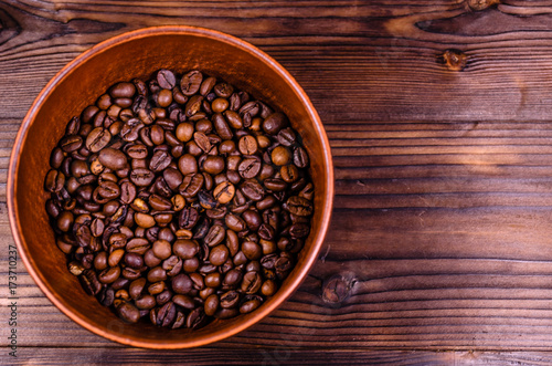 Roasted coffee beans in bowl on wooden table. Top view