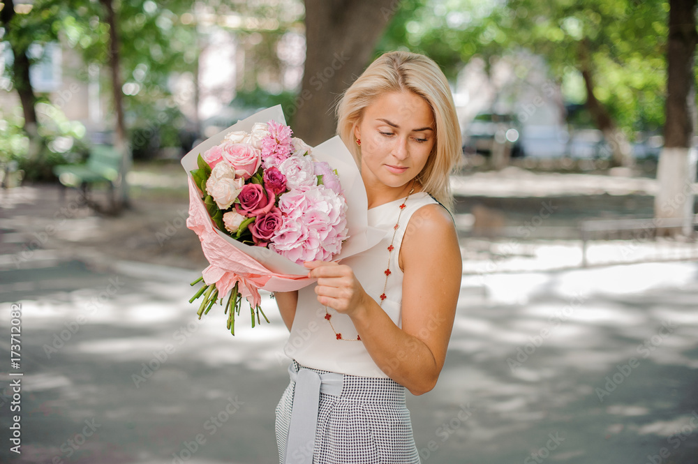 Fototapeta premium Blond woman holding a beautiful composition of flowers