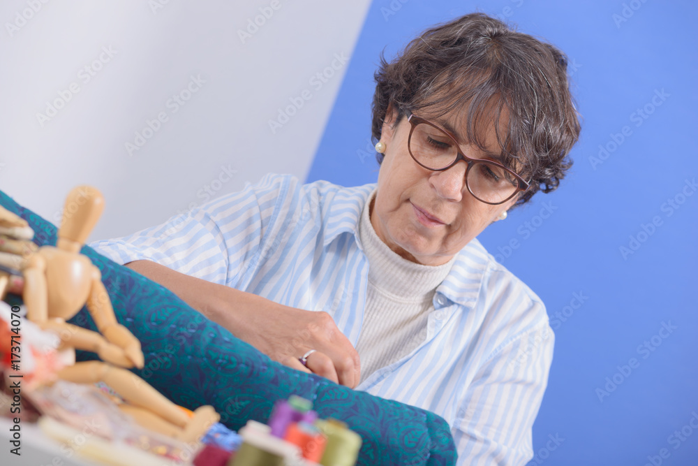 Naklejka premium mature brunette woman sewing patchwork