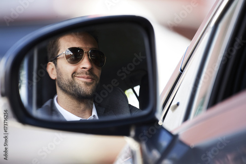 Smiling stubble guy in rear view mirror of car © sanneberg