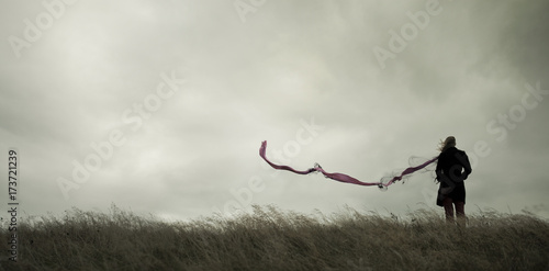 Woman standing alone in harsh weather with dramatic sky photo