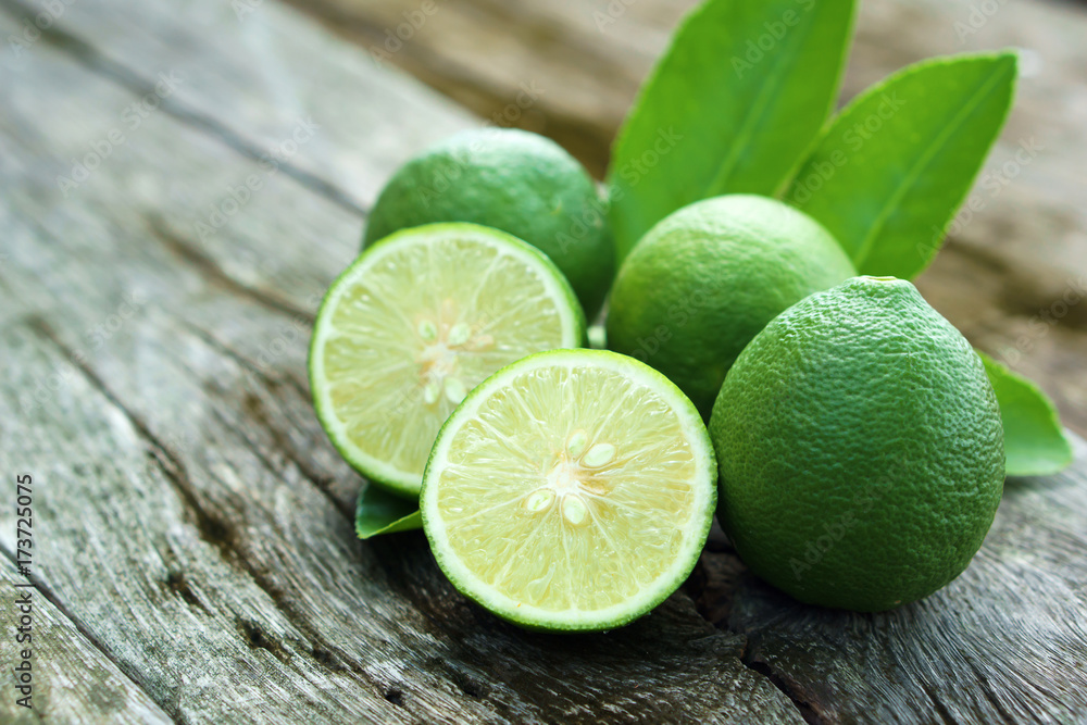 green lemon and lemon slice with leaf on wooden table with copy space green lemon and lemon slice with leaf on wooden table with copy space
