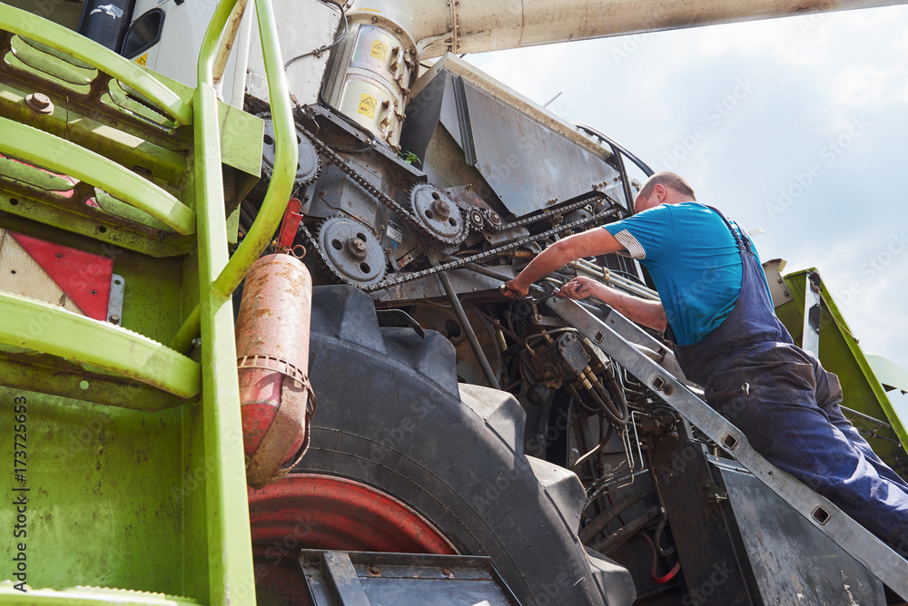 Obraz premium Combine machine service, mechanic repairing motor outdoors