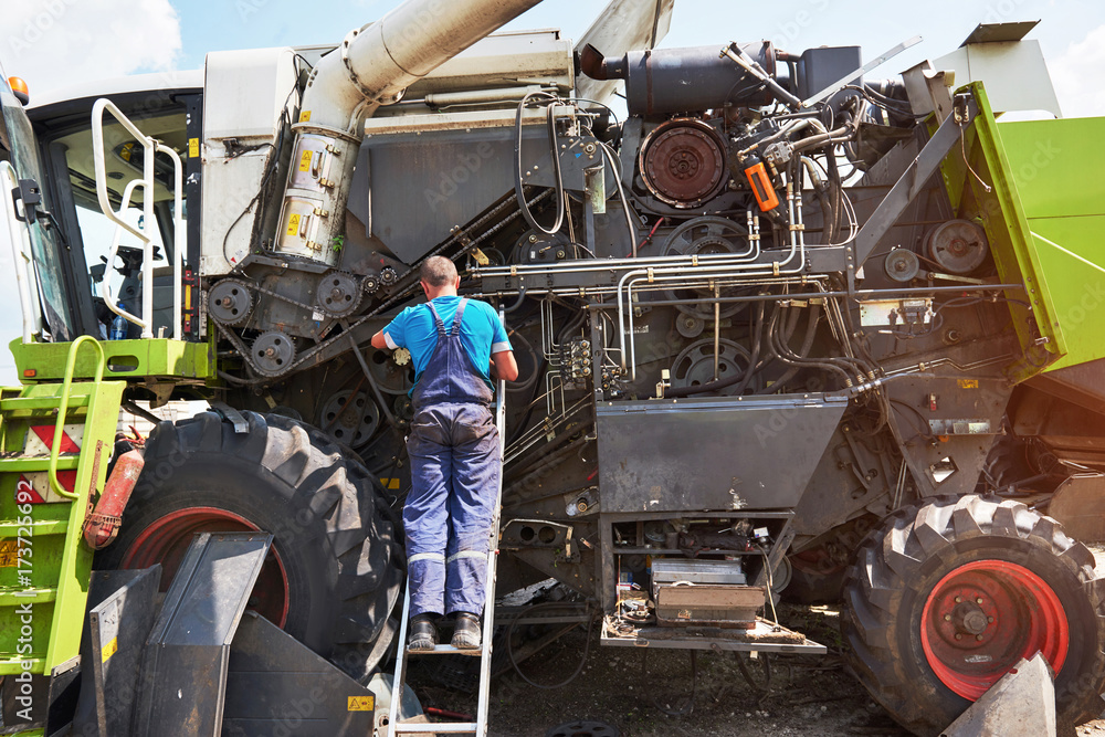 Obraz premium Combine machine service, mechanic repairing motor outdoors