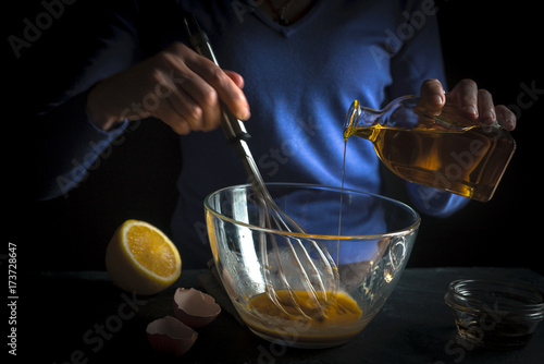Olive oil is poured into whipped yolks for the preparation of mayonnaise