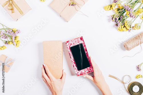 Top view of female hands open a box with a mobile phone
