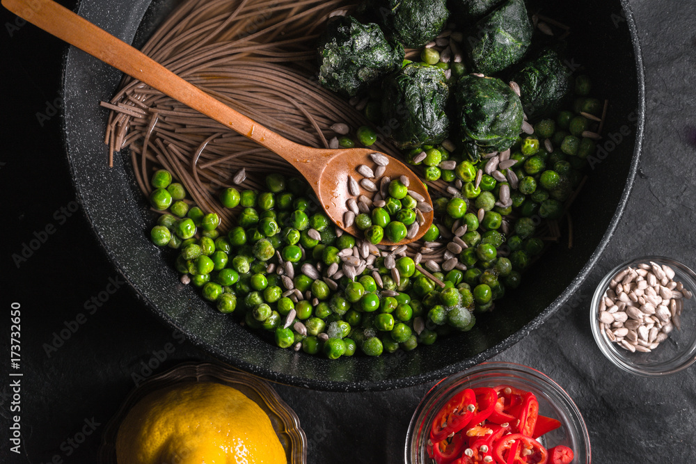 Φωτογραφία Buckwheat noodles in a frying pan, frozen peas and spinach, chillies and seeds i