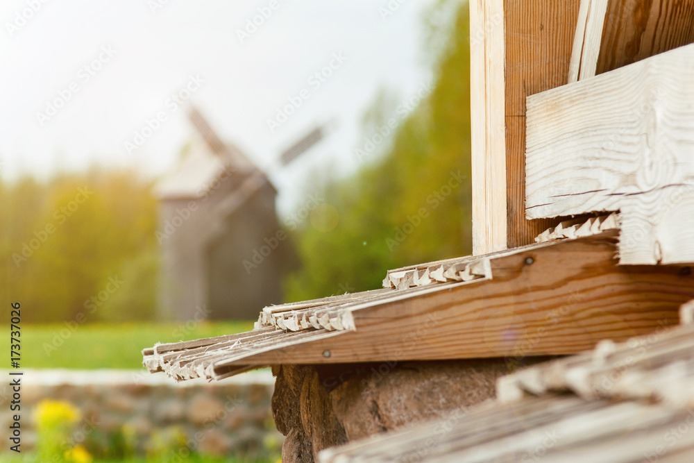 Obraz premium Autumn landscape against the background of a wooden windmill. Wooden windmill in the forest. Autumn landscape in the forest