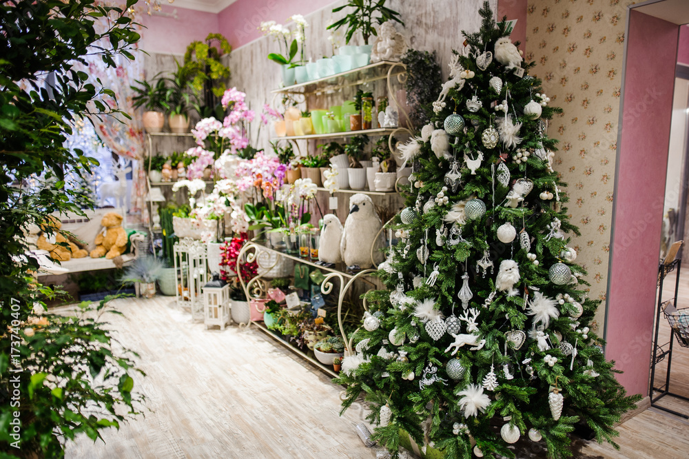 Christmas tree is decorated with white and silvery toys in the decor shop