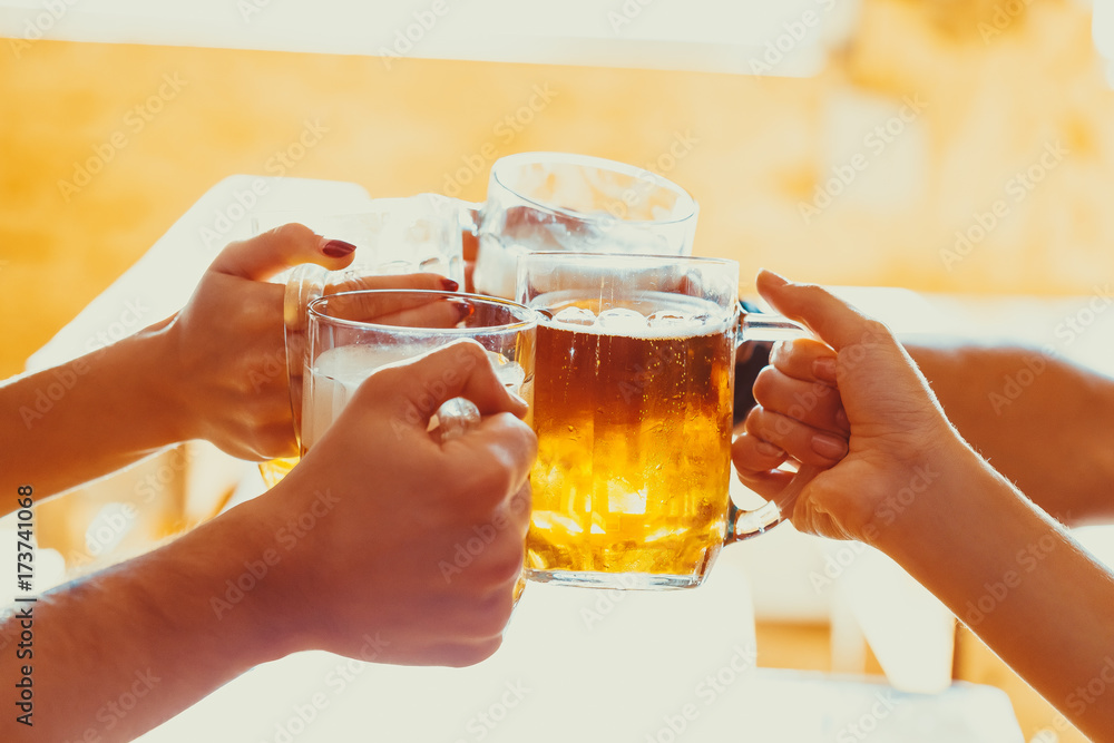 Friends toasting with glasses of light beer at the pub. Beautiful background of the Oktoberfest. A group of young people while relaxing at the bar. fine grain. Soft focus. Shallow DOF Friends toasting with glasses of light beer at the pub. Beautiful background of the Oktoberfest. A group of young people while relaxing at the bar. fine grain. Soft focus. Shallow DOF