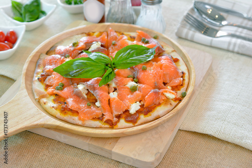 Salmon pizza on wooden plate cutting board style