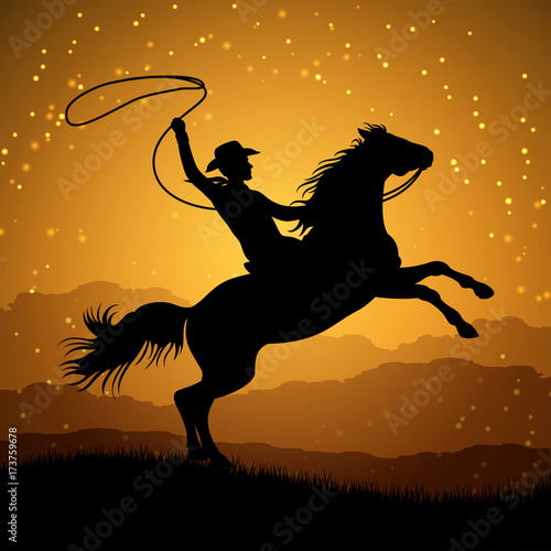 Silhouette of cowboy with lasso on rearing horse