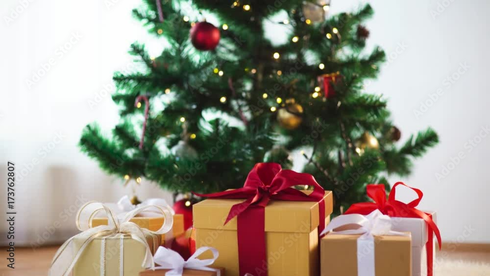hands putting gift boxes under christmas tree hands putting gift boxes under christmas tree