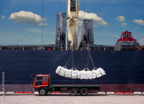 Картината върху платно Sugar bags are loading in hold of bulk-vessel at industrial port,Pick up sugar bags from truck to  loading on board
