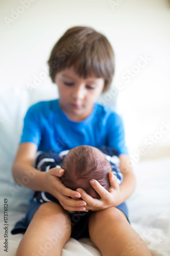 Cute boy, brother, meeting for the first time his new baby brother at hospital