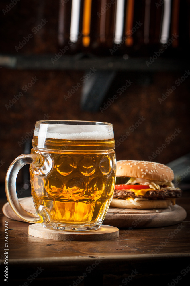A glass of fresh cold light beer with gourmet hamburgers and wheat in a bar and a dark pub