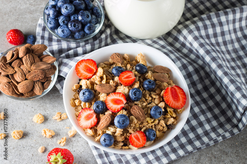 Healthy breakfast concept with oat flakes and fresh berries on rustic background. Food made of granola, muesli. Healthy banana smoothie with blackberries, muslie, strawberries, blueberries and honey.