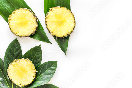 Tropical fruits concept. Pattern of pinneapple slices and leaves on white background top view copyspace photo