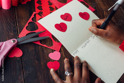 African American girl's hand writing a valentine card