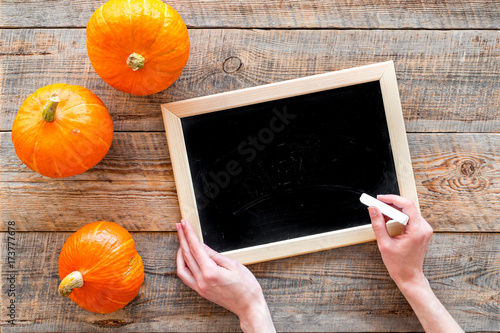 Halloween mockup. Chalkboard near pumpkins on wooden background top view photo