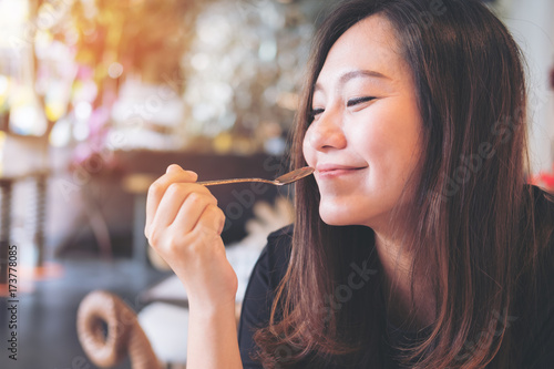 Canvas Print Closeup image of a beautiful Asian woman holding a spoon while enjoy eating food
