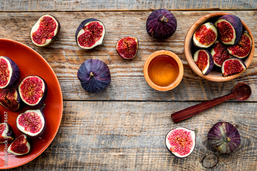 Fresh blue figs in bowl and honey on wooden background top view copyspace