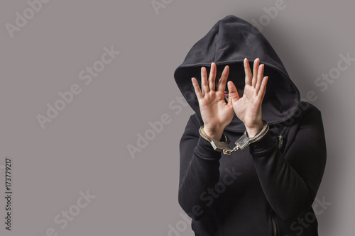 Slika na platnu a girl in a black hood with handcuffed hands hides her face