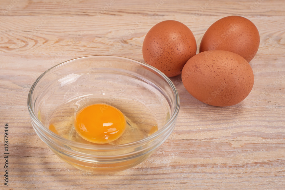 Egg with cracked eggshell on rustic wood table, yolk closeup Egg with cracked eggshell on rustic wood table, yolk closeup