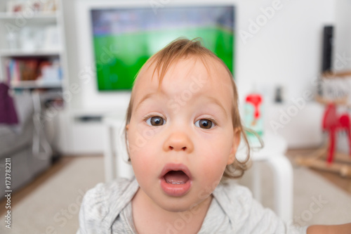 Obraz na plátne One and a half year old toddler girl looking at the camera with her eyes wide op