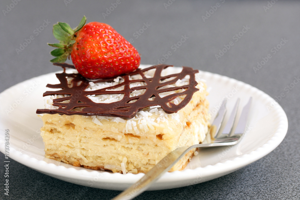 slice of decorated with chocolate and strawberry napoleon cake, served on white plate slice of decorated with chocolate and strawberry napoleon cake, served on white plate