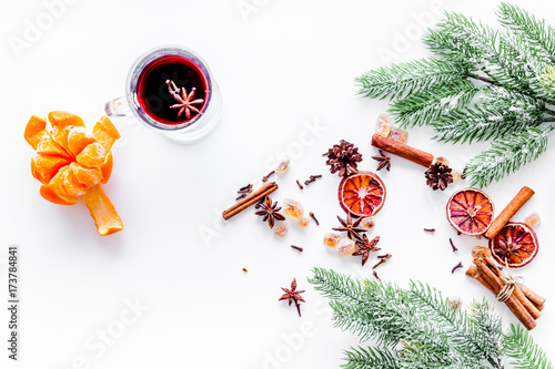 Hot mulled wine or grog cooking for new year celebration with oranges and spices ingredients on white background flat lay mockup