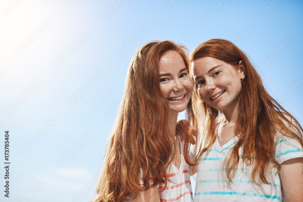 Two ginger girls looking at camera smiling on a sunny summer day. Having a twin sister is a great luck. Two ginger girls looking at camera smiling on a sunny summer day. Having a twin sister is a great luck.