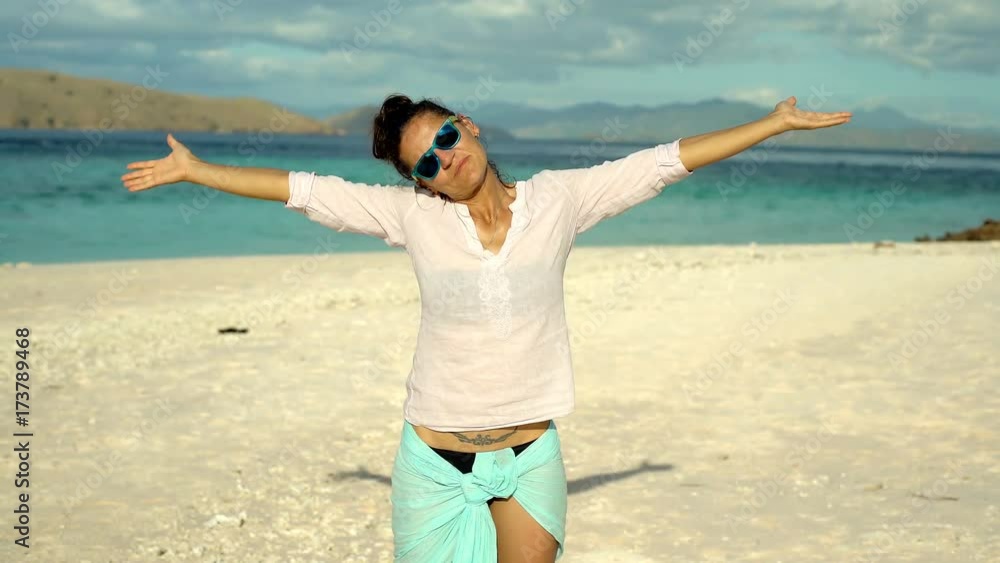 Attractive woman holding her hands up and looks happy on the beach, steadycam shot
Attractive woman holding her hands up and looks happy on the beach, steadycam shot