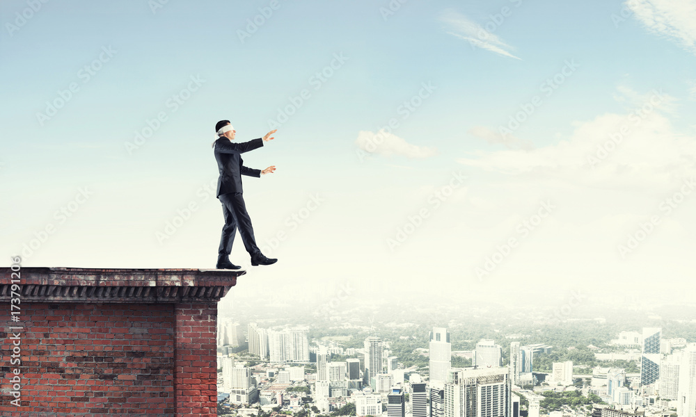 Danger and risk concept with businessman making step from edge Danger and risk concept with businessman making step from edge