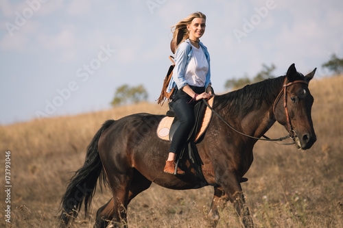 Beautiful young cowgirl riding her horse in field © antgor
