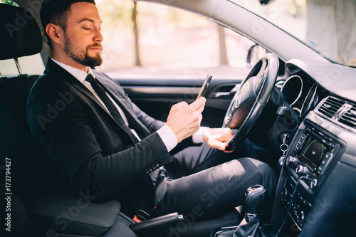 Portrait of handsome business man use phone in car while drive photo