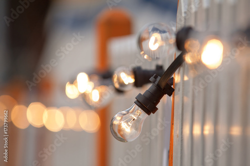 The wooden plaque fence with the decorative chain created from glowing bulbs.