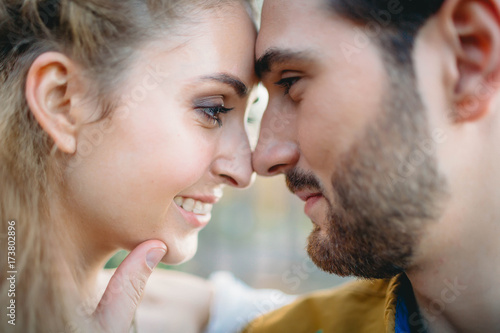 A young couple smile and touching foreheads. Autumn wedding ceremony outdoors. Bride and groom look at each other with tenderness and love. Close-up portrait