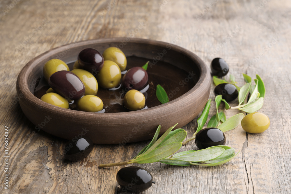 Dish with different olives on wooden table Dish with different olives on wooden table