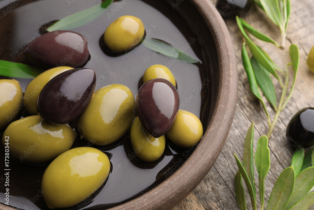 Dish with different olives on wooden table, closeup Dish with different olives on wooden table, closeup