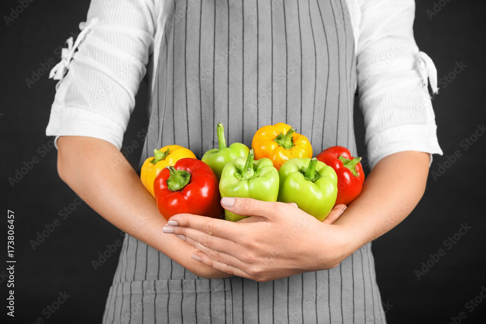 Woman holding paprika peppers on black background Woman holding paprika peppers on black background