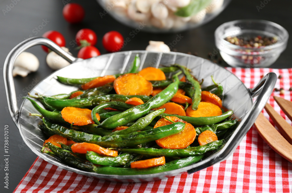 Delicious green beans and carrot slices in frying pan on kitchen table Delicious green beans and carrot slices in frying pan on kitchen table
