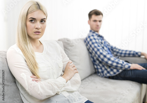 The sad woman sit near the man on the sofa